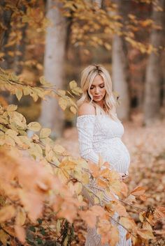 a pregnant woman is standing in the leaves