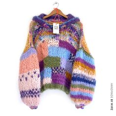 a colorful sweater hanging on a hanger with a tag attached to the top of it