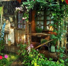 an old shed is covered in plants and flowers