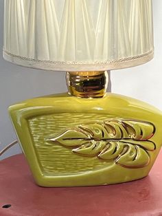 a yellow lamp sitting on top of a pink table next to a white lampshade