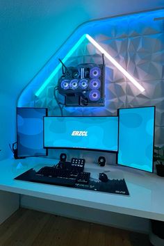 a desk with a computer and speakers on it in front of a blue light wall