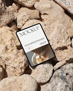 a book sitting on top of a pile of rocks next to a white object with the word mockup written in it