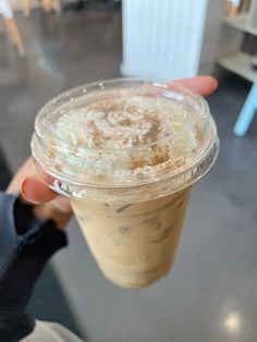 a person holding up a plastic cup filled with ice cream and cinnamon sprinkles