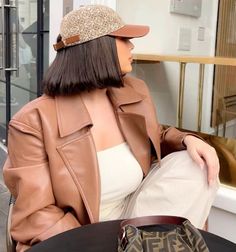 a woman sitting at a table with a handbag in front of her and wearing a hat