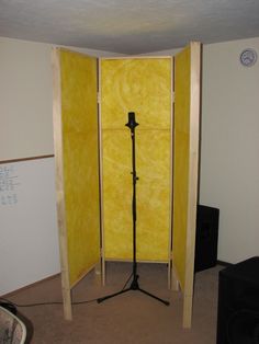 an empty room with yellow walls and a black tripod in the corner next to it