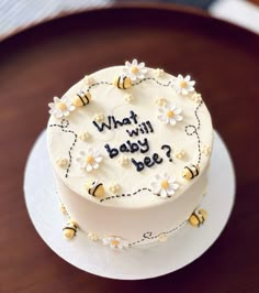 a cake that is sitting on top of a wooden table with the words what will baby bee written on it