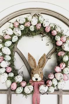 an easter wreath with eggs and a bunny in the middle is hung on a door