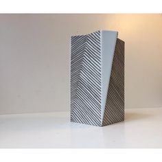 a white vase sitting on top of a table next to a light fixture with a black and white pattern