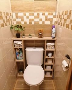 a white toilet sitting inside of a bathroom next to a wooden shelf filled with items