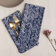 a napkin with a fork on it next to a plate and flower vase, along with a gold utensil