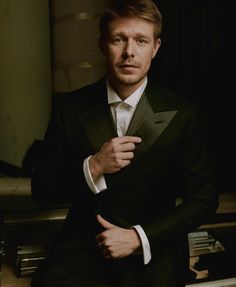 a man in a tuxedo is posing for a photo with his hands on his lapel