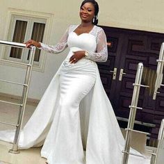 a woman in a white wedding dress standing on steps with her hand on the rail