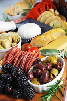 a wooden table topped with different types of foods and cheeses on top of it