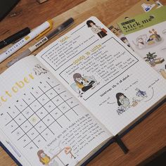 an open planner with stickers and pens on it sitting on a wooden table next to a cup of coffee