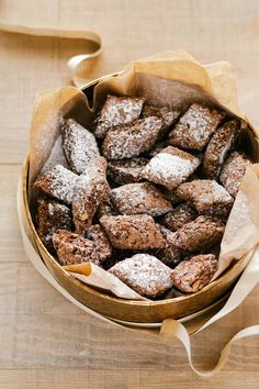 a bowl filled with brownies covered in powdered sugar on top of a wooden table