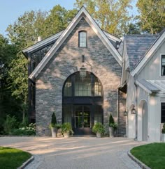 a large brick and stone house in the middle of a driveway with trees around it