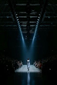 a person walking down a runway in the dark