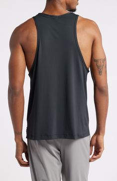 a man in grey shorts and a black tank top is looking down at his back