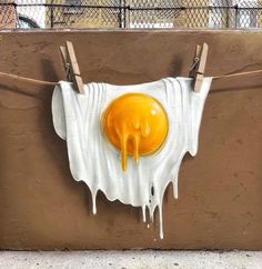 an egg is hanging on a clothesline with melted paint dripping down the top and bottom