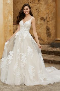 a woman in a white wedding dress standing on steps with her arms behind her back