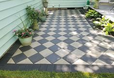 a black and white checkerboard patio in front of a house with potted plants