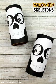 two paper cups decorated with black and white skulls on wooden boards, one has the word halloween skeletons painted on it