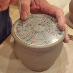 a person is working on a clay pot with a compass in the shape of a wheel