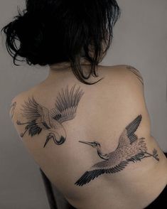 the back of a woman's shoulder with two birds on it and one bird in flight