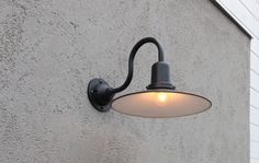 an outdoor wall light on the side of a building with a white light shining in it