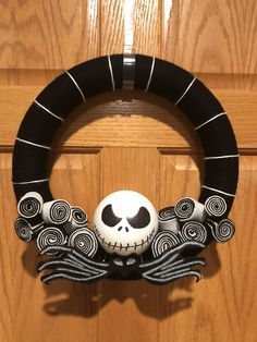 a black and white wreath with a skull on it's side hanging from the front door