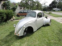 an old white car is parked in the grass