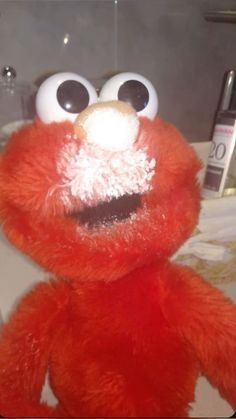 a red stuffed animal sitting on top of a bathroom sink next to a toothbrush