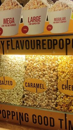 three buckets of popcorn sitting on top of a counter next to each other in front of a sign