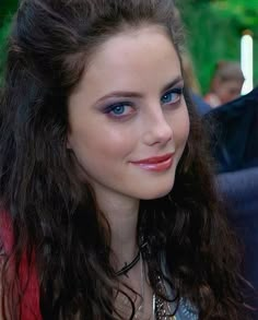 a close up of a woman with long hair and blue eyes smiling at the camera