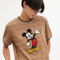 Beloved Disney characters meet iconic Coach design in this special collection starring the one-and-only Mickey Mouse and friends. Mickey Mouse is front and center set against our Signature on this classic-fit T-shirt. Finished with contrast trim the short sleeve style is crafted of a soft cotton-blend. | Disney X Coach Signature Mickey Mouse T-Shirt - Women's Size XS - Tan Signature Coach Disney, Travel Jacket, Mickey Mouse T Shirt, Mickey Mouse And Friends, Disney Style, Contrast Trim, Outerwear Jackets, Dresses For Sale, Sleeve Styles