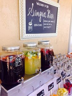 there are many drinks on the bar with labels in mason jars and glasses lined up next to each other