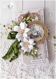 a close up of a card with flowers and leaves on the front, along with a lace doily