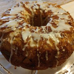 a glazed donut sitting on top of a glass cake plate covered in icing