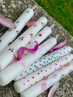 several white candles with designs on them sitting on a rock