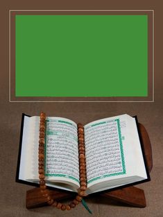 an open book sitting on top of a wooden stand next to a green screen background