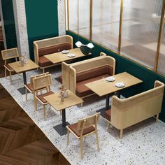 an empty restaurant with wooden tables and chairs in front of the window, along with green walls