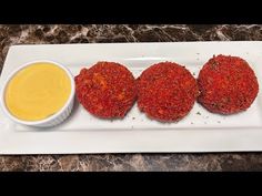 three crab cakes on a white plate with dipping sauce