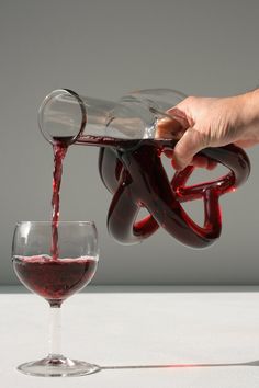 someone pouring red wine into a glass in front of a white background with arabic writing