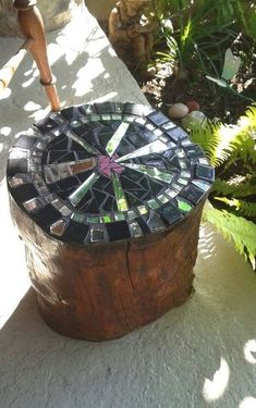 a wooden box with a mosaic design on the top and sides, sitting in front of some plants