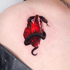 a red and black snake tattoo on the back of a woman's shoulder