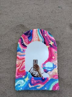 a person taking a selfie in front of a colorful mirror on the ground with their reflection