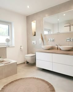 a bathroom with two sinks and a bathtub next to a large round rug on the floor