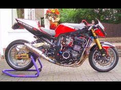 a red and black motorcycle parked on top of a brick road next to a building