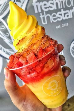 someone is holding up a sundae with strawberries and bananas on top, in front of a poster