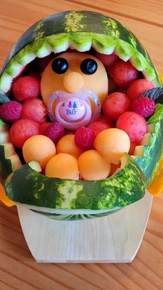 a watermelon sculpture with a pacifier in it's mouth filled with fruit